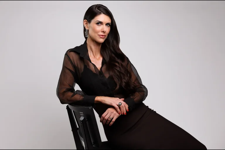 Dra. Monique Bins sentada em uma cadeira, usando roupa preta